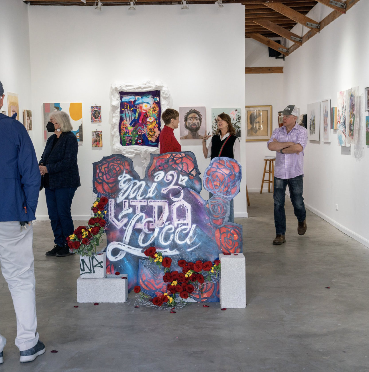 Documentary photograph: an artist and visitors together in a studio during Art Walk. People and artwork in the same frame.